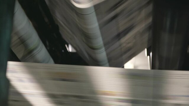 Newspapers rolling on printing press.
