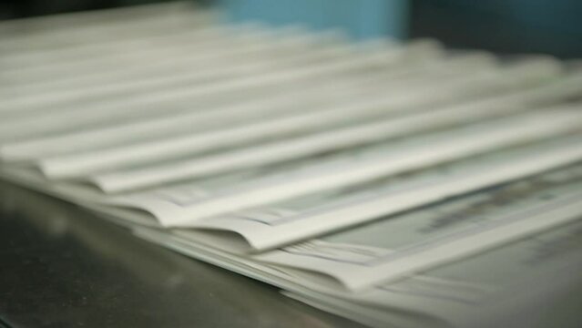 Printed newspapers move along a conveyor belt.
