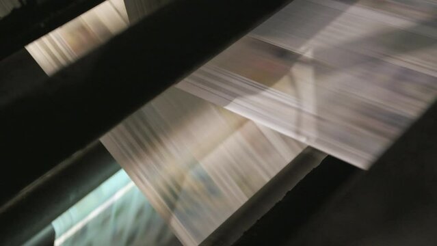Newspapers rolling on printing press.
