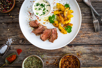 Grilled pork loin steaks with fried potatoes on wooden table
