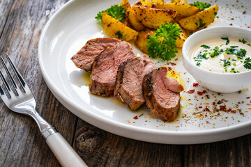 Grilled pork loin steaks with fried potatoes on wooden table
