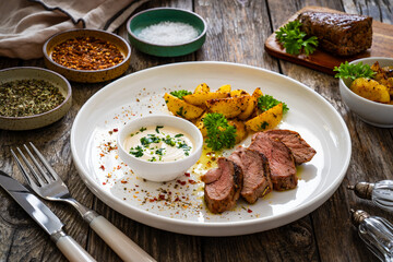 Grilled pork loin steaks with fried potatoes on wooden table
