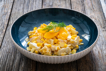 Fruit salad - peaches, pineapples, almonds and corn in mayonnaise on wooden table
