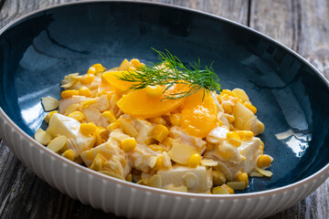 Fruit salad - peaches, pineapples, almonds and corn in mayonnaise on wooden table