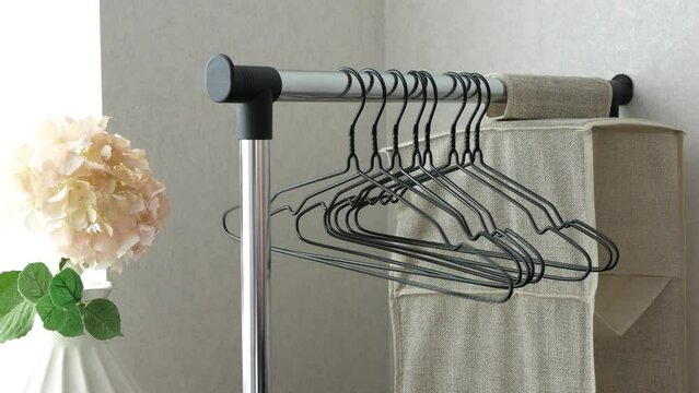Hand hangs clothes hangers on the clothes rod, selective focus. Concept of home storage, space saving tools, keeping clothing organized