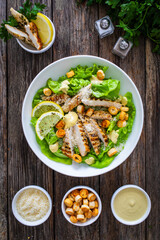 Caesar salad - fried chicken breast and vegetables on wooden table
