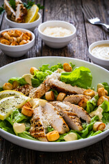 Caesar salad - fried chicken breast and vegetables on wooden table
