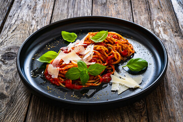 Spaghetti marinara with parmesan cheese and basil leaves served on wooden table
