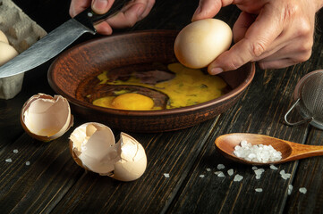 The concept of cooking an egg dish. Work environment on the kitchen table with groceries and eggs. Egg in the chef hand