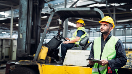 Industrial worker driving a forklift in the factory. Efficient Logistics Management and Teamwork in Manufacturing and Distribution Industry.