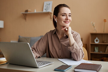 Portrait of smiling businesswoman working from home and looking at window pensively, copy space