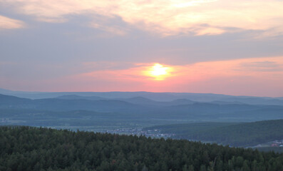 Sunset over mountains and countryside village, sky in soft pastel colors.