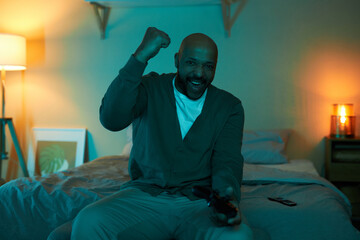 Fototapeta premium Front view portrait of excited adult black man playing video games in dark and celebrating victory, copy space