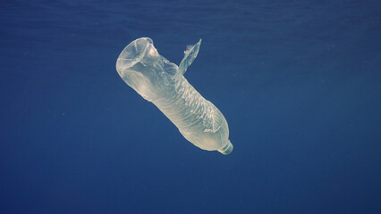 Disposable plastic bottle drift under surface of blue water. A plastic bottle is thrown into sea...