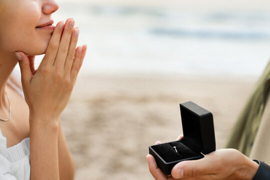 Engagement. Man asking his girlfriend the marriage question, proposing marry him on the beach, closeup, cropped