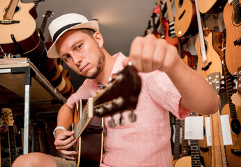 Young musician tuning a classical guitar in a guitar shop