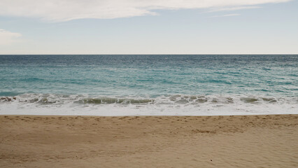 Clear blue waves with strong wind on a sandy empty beach in Cannes in spring
