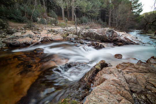 Fotografía del río de La Pedriza con una cascada y aguas cristalinas: La imagen muestra el río de La Pedriza fluyendo suavemente entre las rocas, con una hermosa cascada en el fondo. 