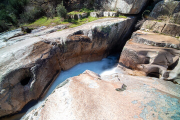 Fotografía de una cascada: Una imagen que muestra una cascada en el río de La Pedriza. El agua cae en cascada desde lo alto de una formación rocosa, creando un hermoso efecto de movimiento.