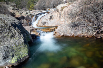 Fotografía del río de La Pedriza con una cascada y aguas cristalinas: La imagen muestra el río de La Pedriza fluyendo suavemente entre las rocas, con una hermosa cascada en el fondo.