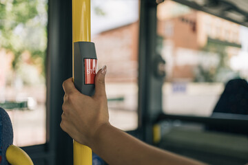 Woman's hand operating the bus stop request button. Close up image of a young girl's hand pressing...