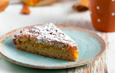 Baked pie served with hot tea on table with dried leaves and walnuts autumn composition