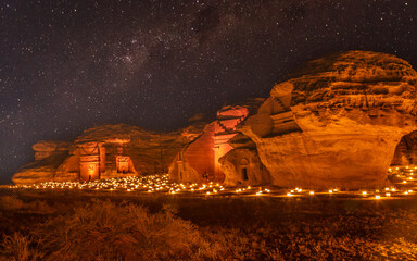 Starlight sky over the ancient nabataean tombs of Hegra city illuminated, night panorama, Al Ula,...
