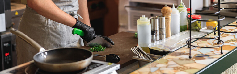 Fototapeta na wymiar Male chef hands using professional knife to chop finely fresh organic herbs for recipe