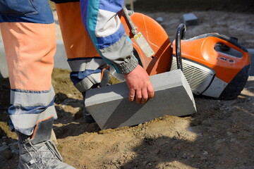 A worker lifts a road curb, repairs a sidewalk for pedestrians.