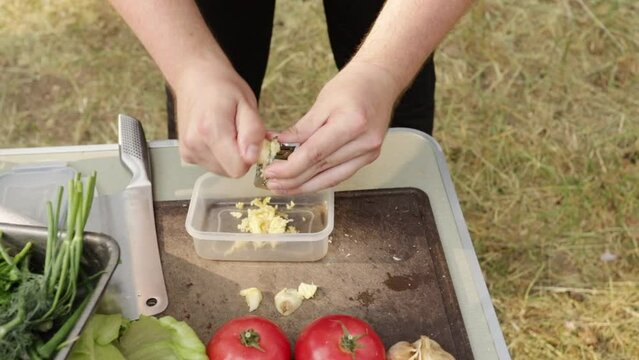 male hands rub garlic on a grater in nature, outdoor cooking, picnic in the forest