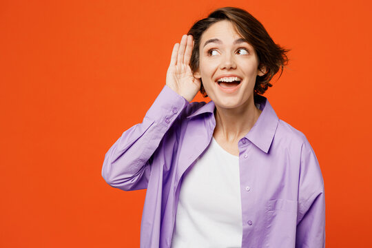 Young curious nosy caucasian woman she wear purple shirt white t-shirt casual clothes try to hear you overhear listening intently isolated on plain orange background studio portrait Lifestyle concept