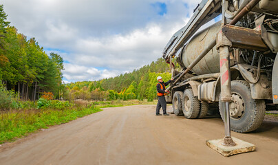Concrete mixer truck in picturesque location. Man near construction equipment. Concrete mixer truck...