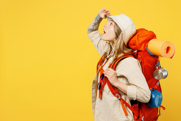 Side view shocked young woman carry backpack with stuff mat look overhead isolated on plain yellow...
