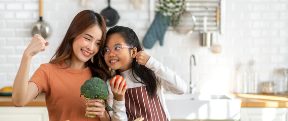 Obraz premium Portrait of enjoy happy love asian family mother and little asian girl daughter child having fun help cooking food healthy eat together with fresh vegetable salad and ingredient in kitchen