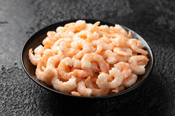 Ready to eat shrimps, prawns in black bowl on rustic background