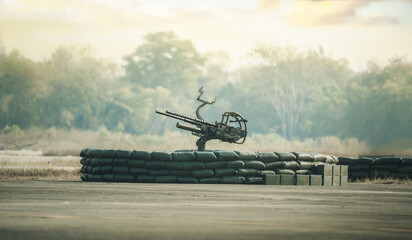 An anti-aircraft cannon and Military  fighting scene. Piece of an anti-aircraft artillery batteries against, World War Soldiers Below Cloudy Skyline at sunset. Attack scene. Armored vehicles.