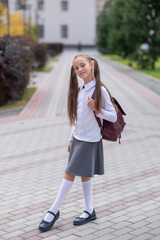 Caucasian girl in uniform and with a backpack goes from school. 