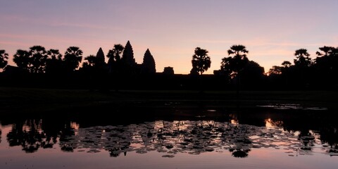Fototapeta premium A serene view of the Angkor Temple and its environs at dusk, with the shadows creating a captivating outline in the Cambodian landscape.