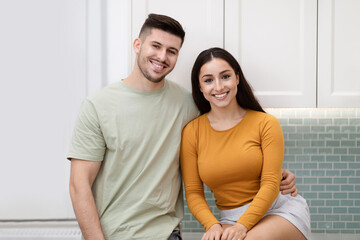 Portrait of happy beautiful young couple posing at kitchen