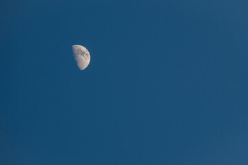 half moon suspended in a clear blue sky