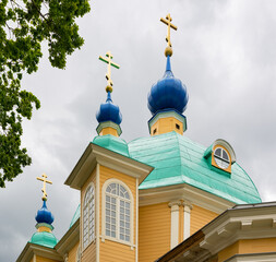 Beautiful yellow wooden church with green copper roof and blue domes in Riga, Latvia.