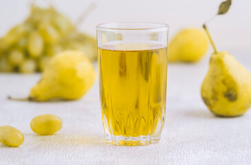 Juice of pears and grapes in a glass on a white wooden background