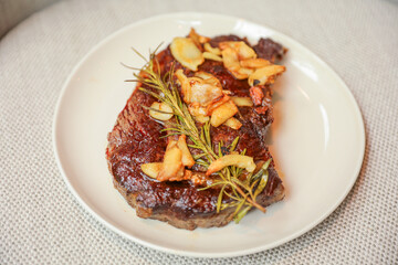 An exquisite steak on a plate adorned with garlic and fresh greens, representing indulgence, culinary excellence, and a balanced gourmet experience