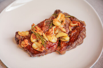 An exquisite steak on a plate adorned with garlic and fresh greens, representing indulgence, culinary excellence, and a balanced gourmet experience