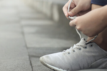 a girl laces her sports shoes before exercising