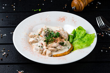 Fried potato pancakes with chicken, bacon, lettuce, sauce and microgreens.