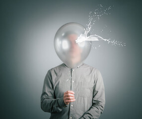 The man hides his face behind a silver balloon. - 619112531