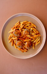 A closeup of Italian style meatballs with tomato sauce and penne