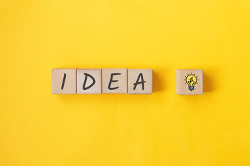 IDEA text on wooden cubes with bulb on yellow background. Thinking new ideas 