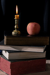 Vintage Still Life: Illuminated Wisdom and Tranquility with an Old Book, Bible, and Candle on a Wooden Table